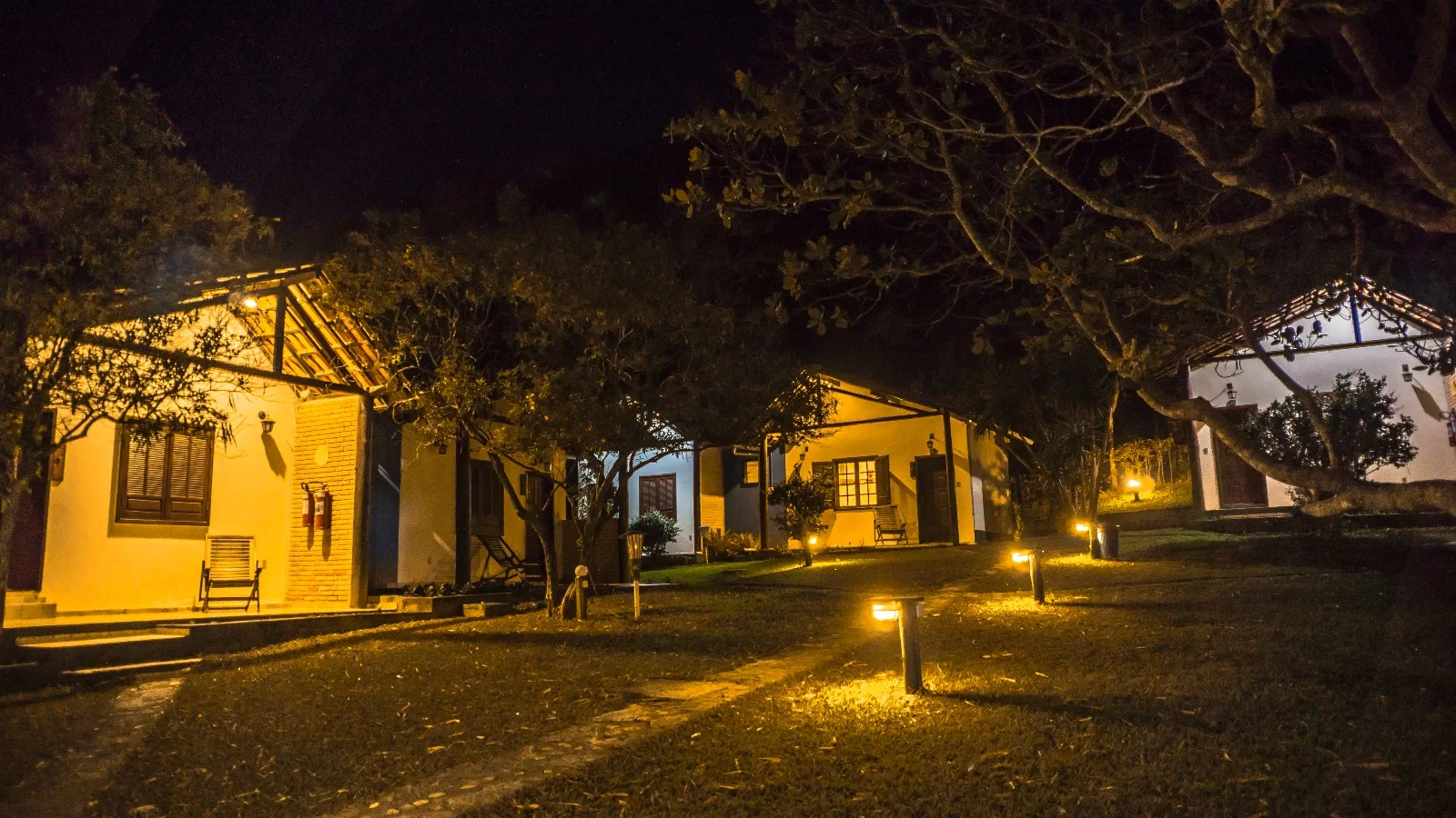 Jardins e chalés da pousada iluminados à noite